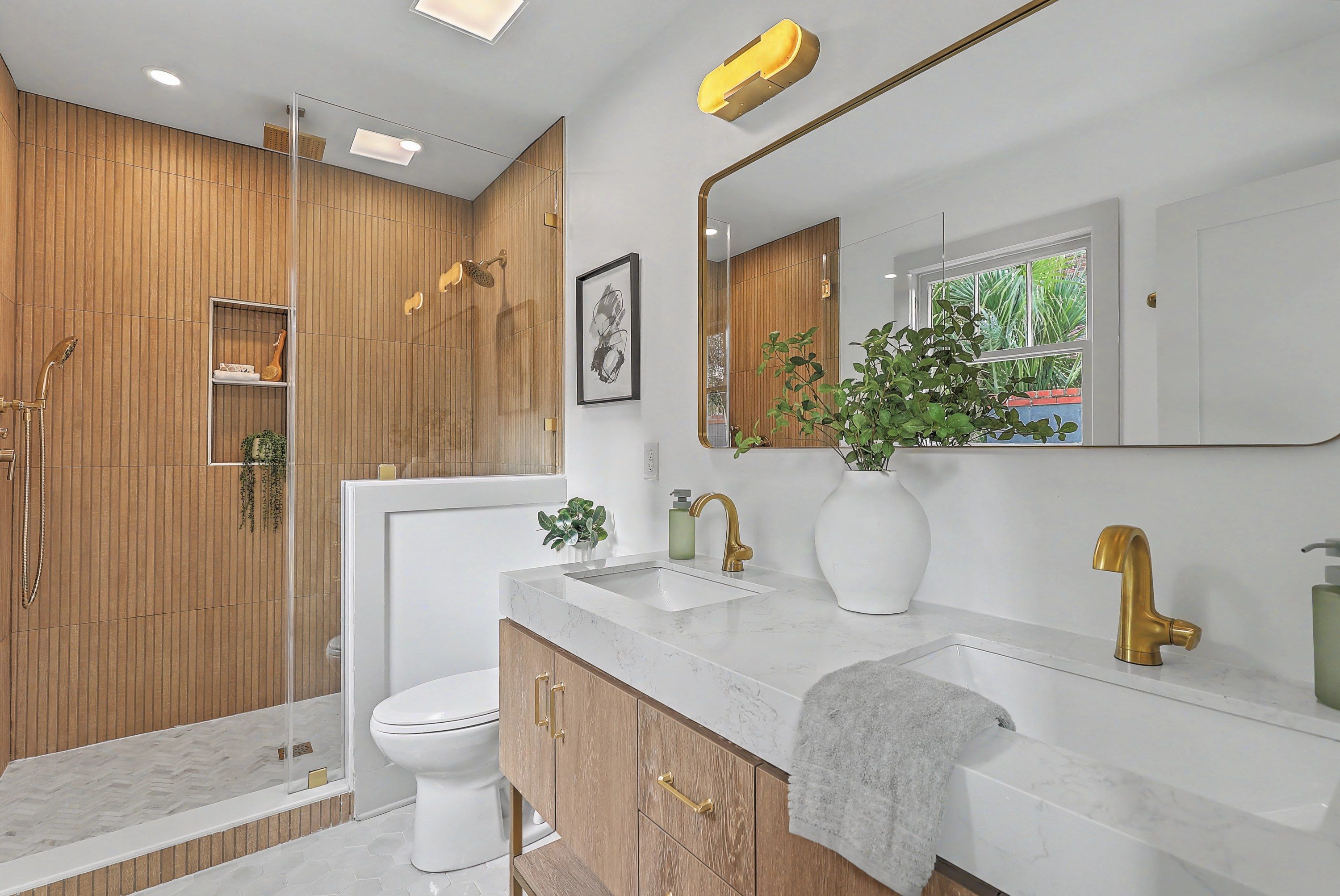 Ensuite bath with fluted wood-look tile shower, double vanity and brass fixtures