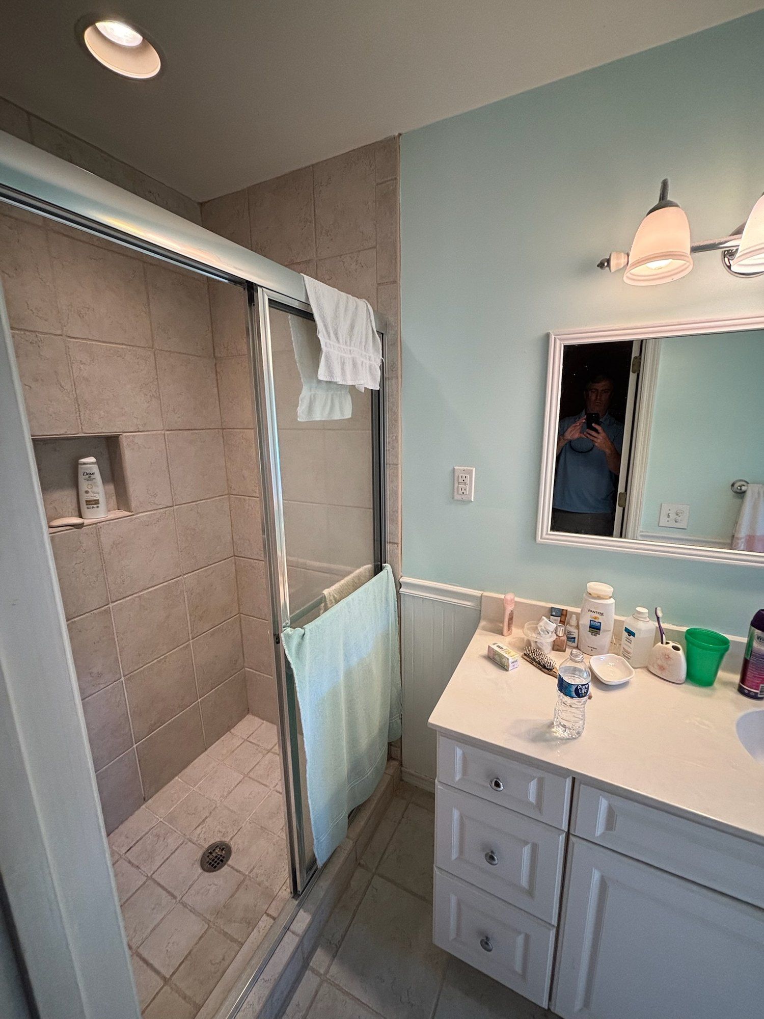 Original bathroom with framed glass shower and dated vanity