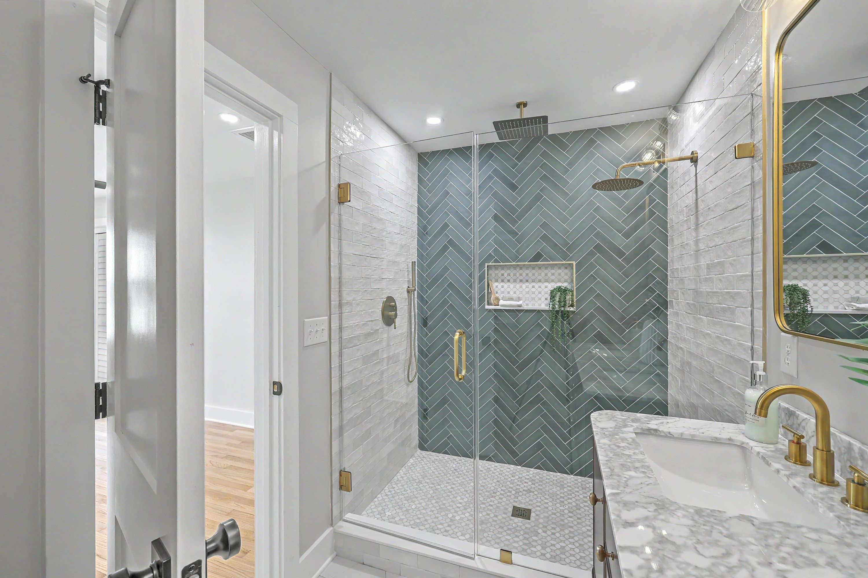 Bathroom with green herringbone tile shower and brass fixtures