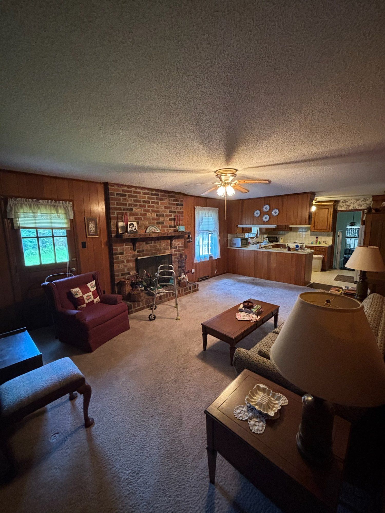 Original wood-paneled family room with brick fireplace and closed-off kitchen