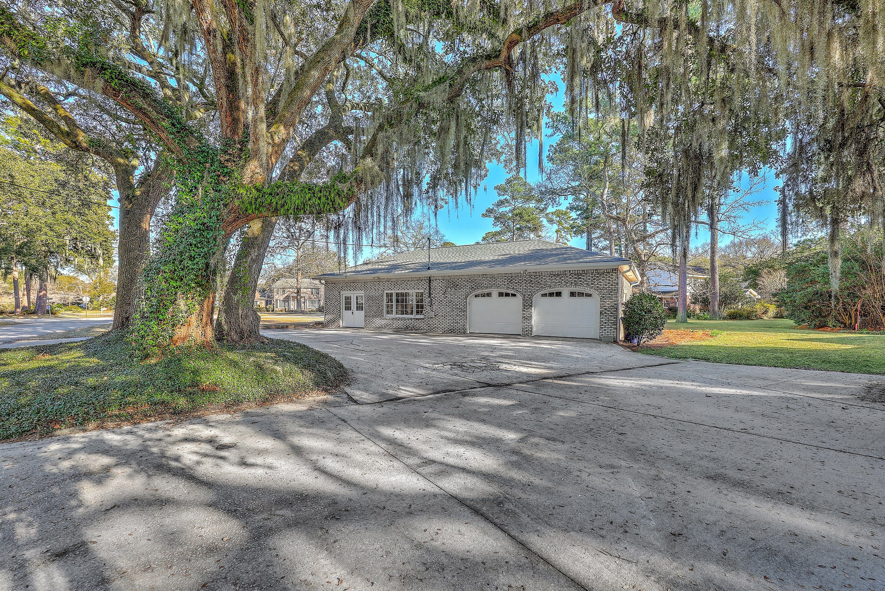 Two-car brick garage and driveway beneath a moss-draped live oak