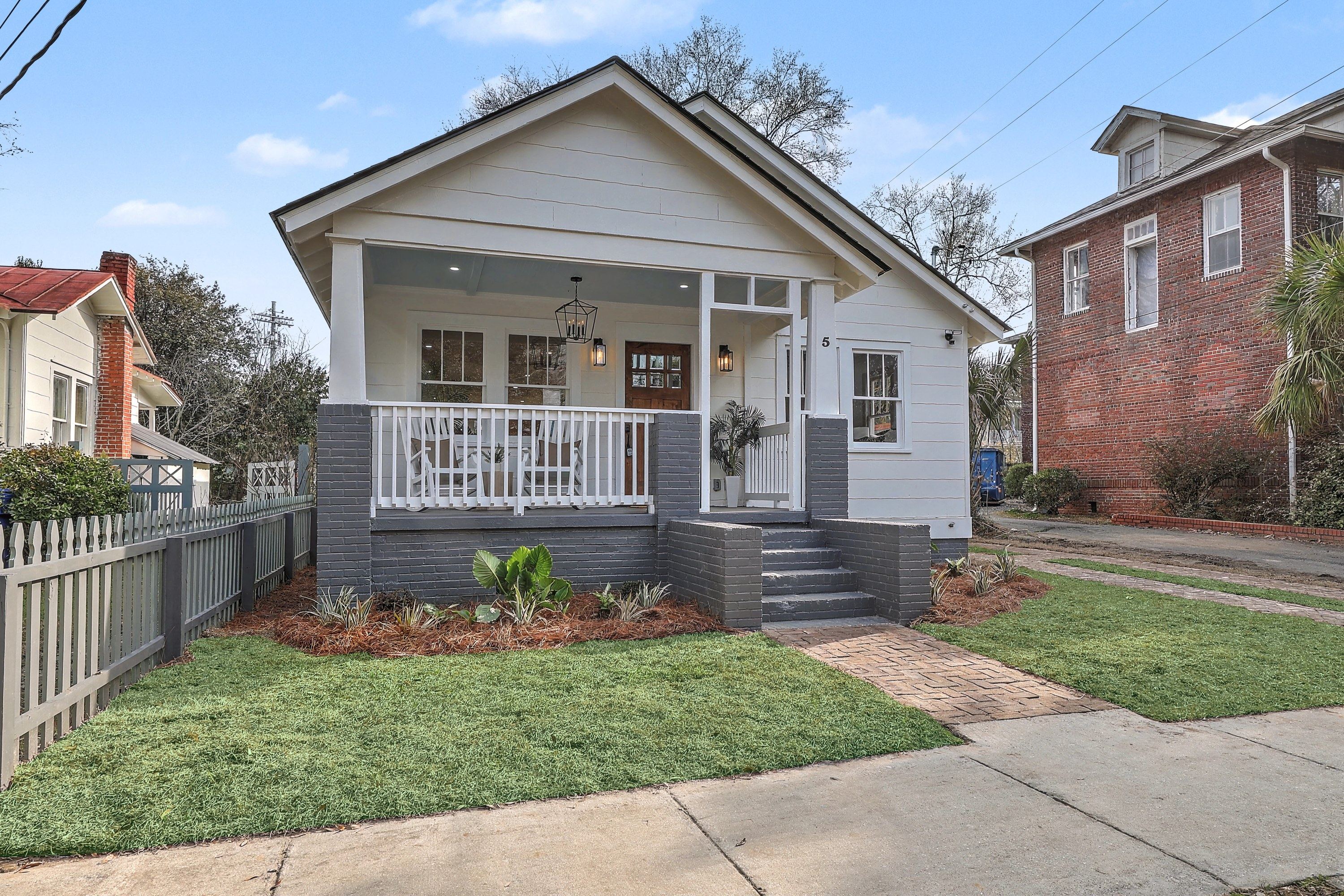 5 Saint Margaret Street after rebuild: white bungalow with a covered front porch, painted brick base and new lawn