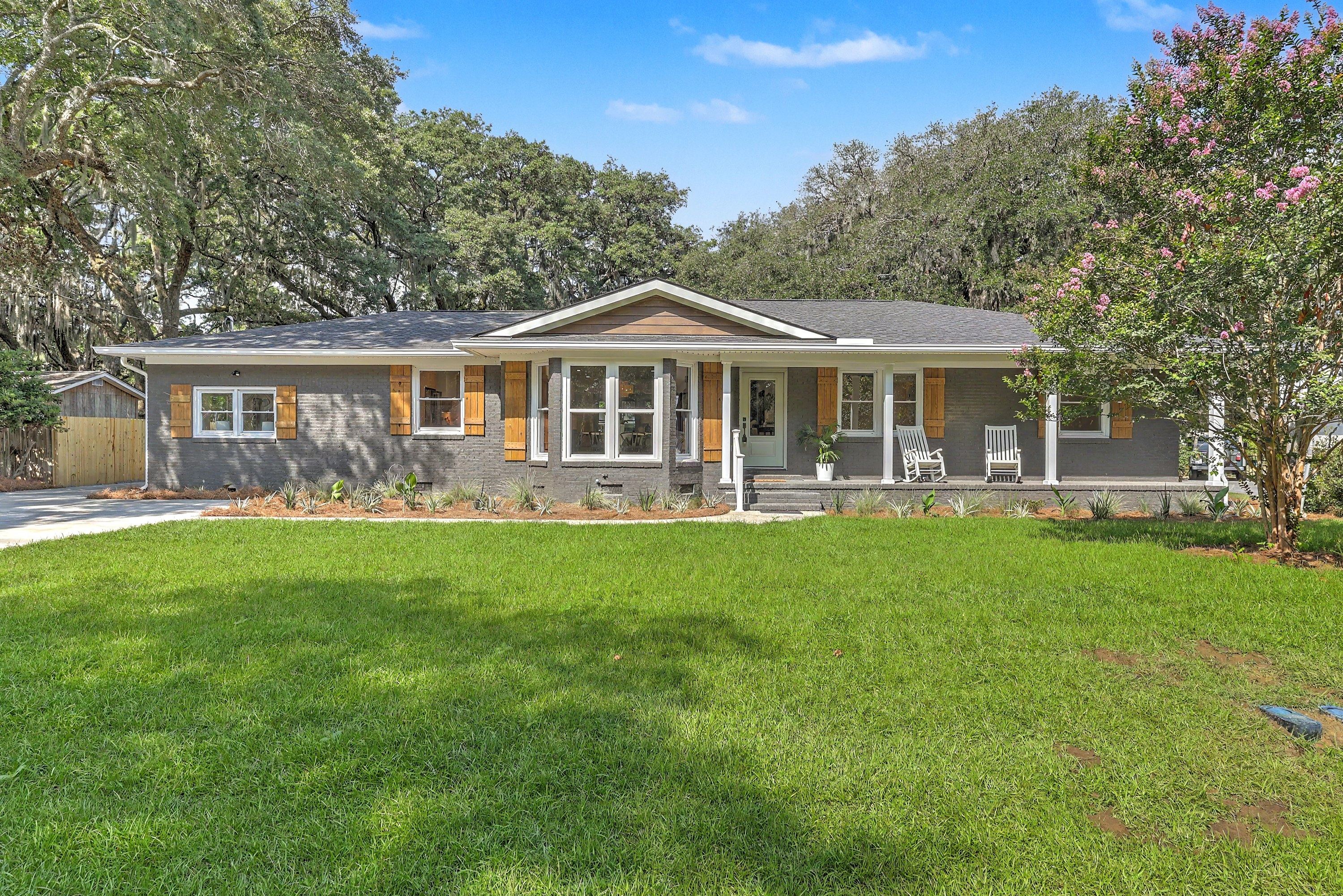 1773 Huntington Drive after renovation: painted brick ranch with cedar shutters, white porch columns and new lawn under live oaks