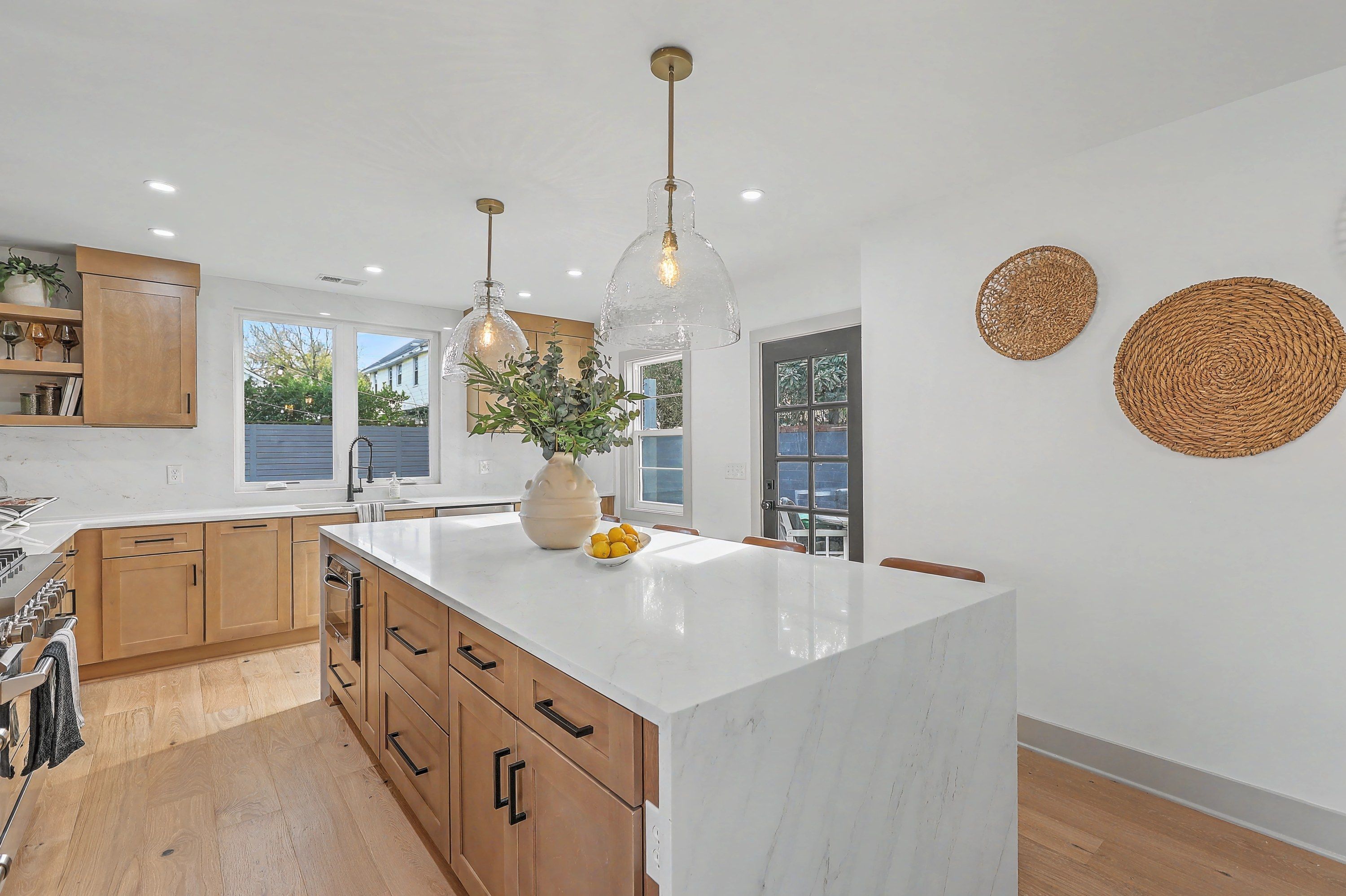 Waterfall island and kitchen windows overlooking the fenced backyard