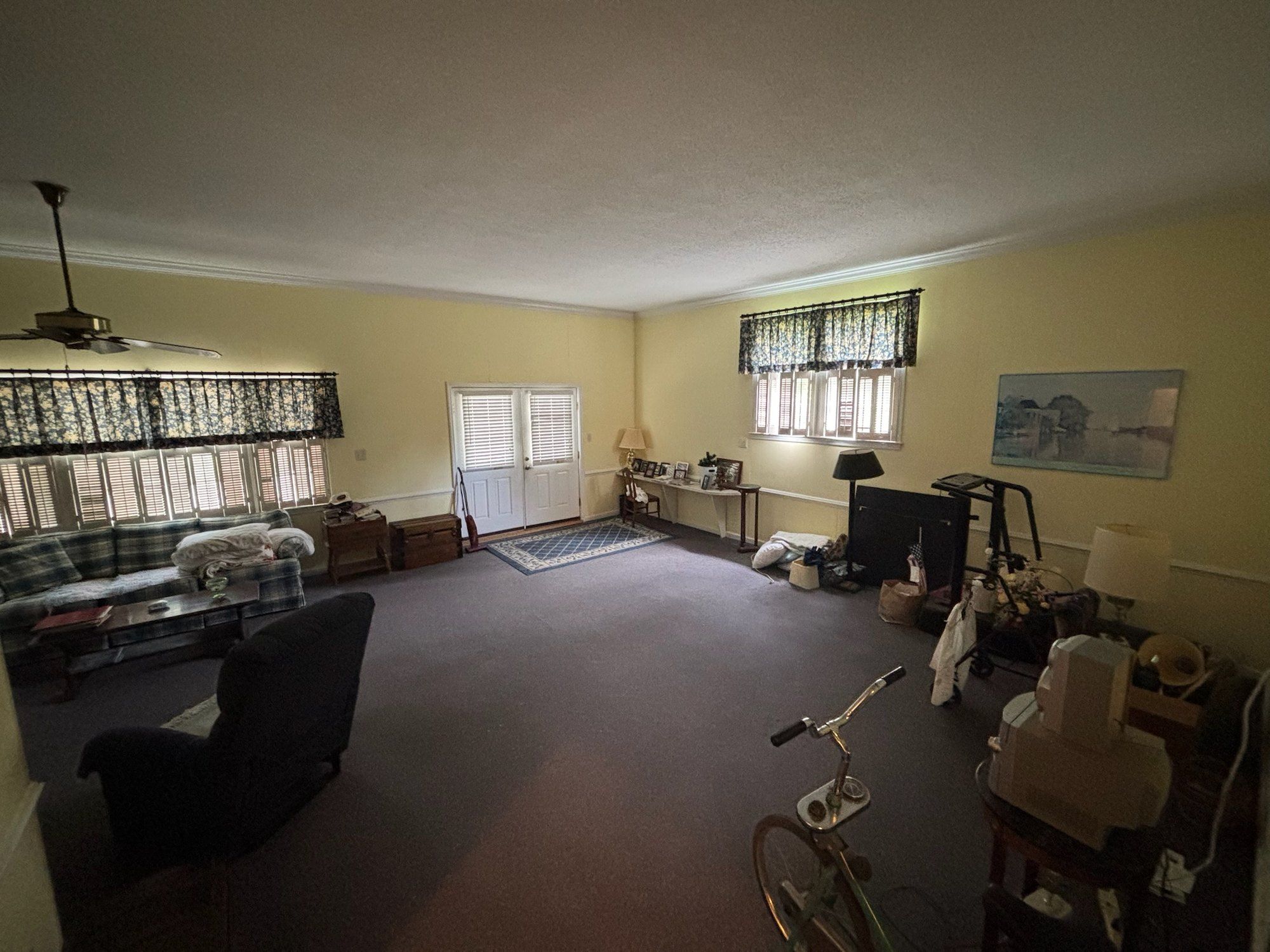 Original large carpeted room with dated window treatments