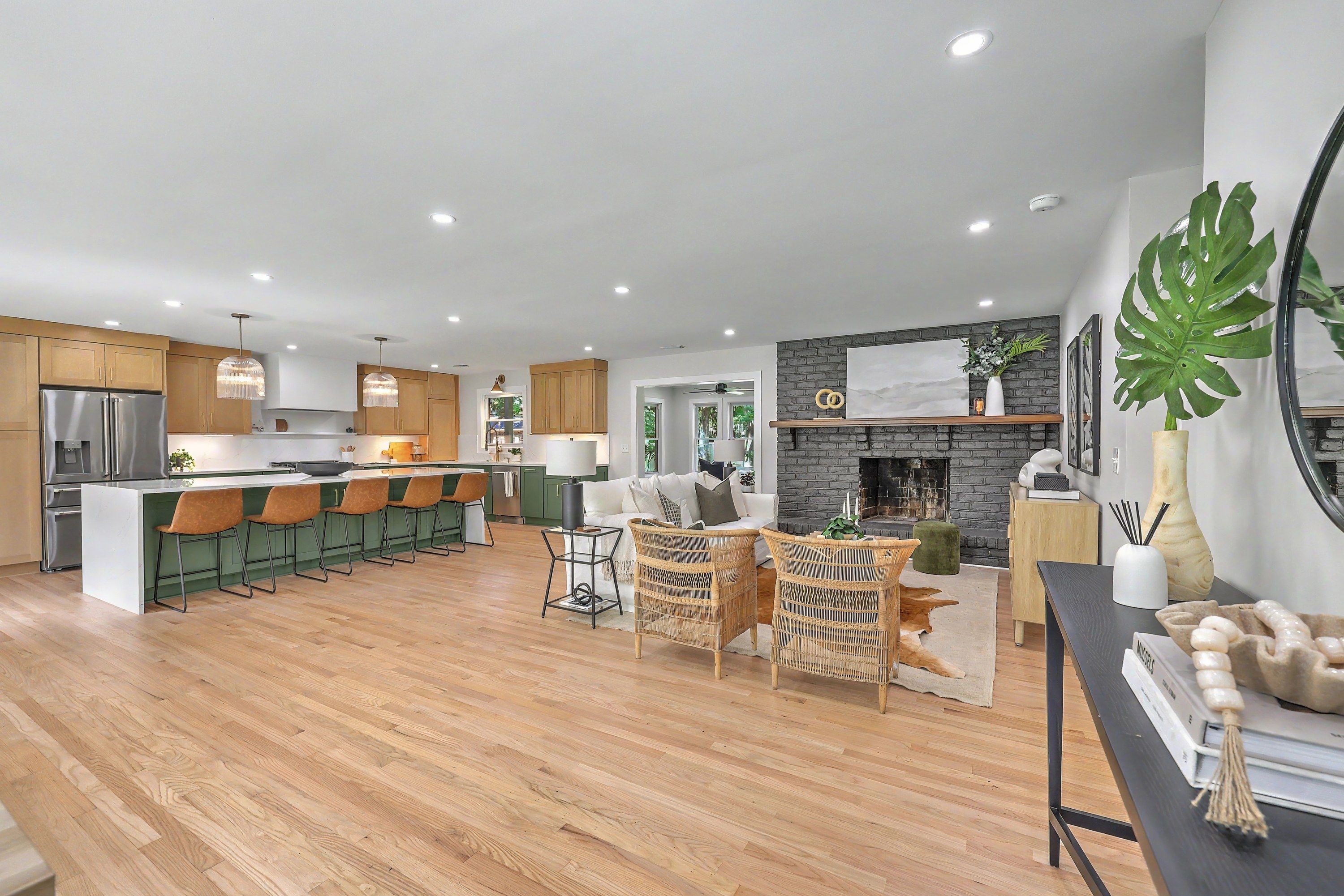 Open living room and kitchen with refinished hardwood floors and a painted brick fireplace