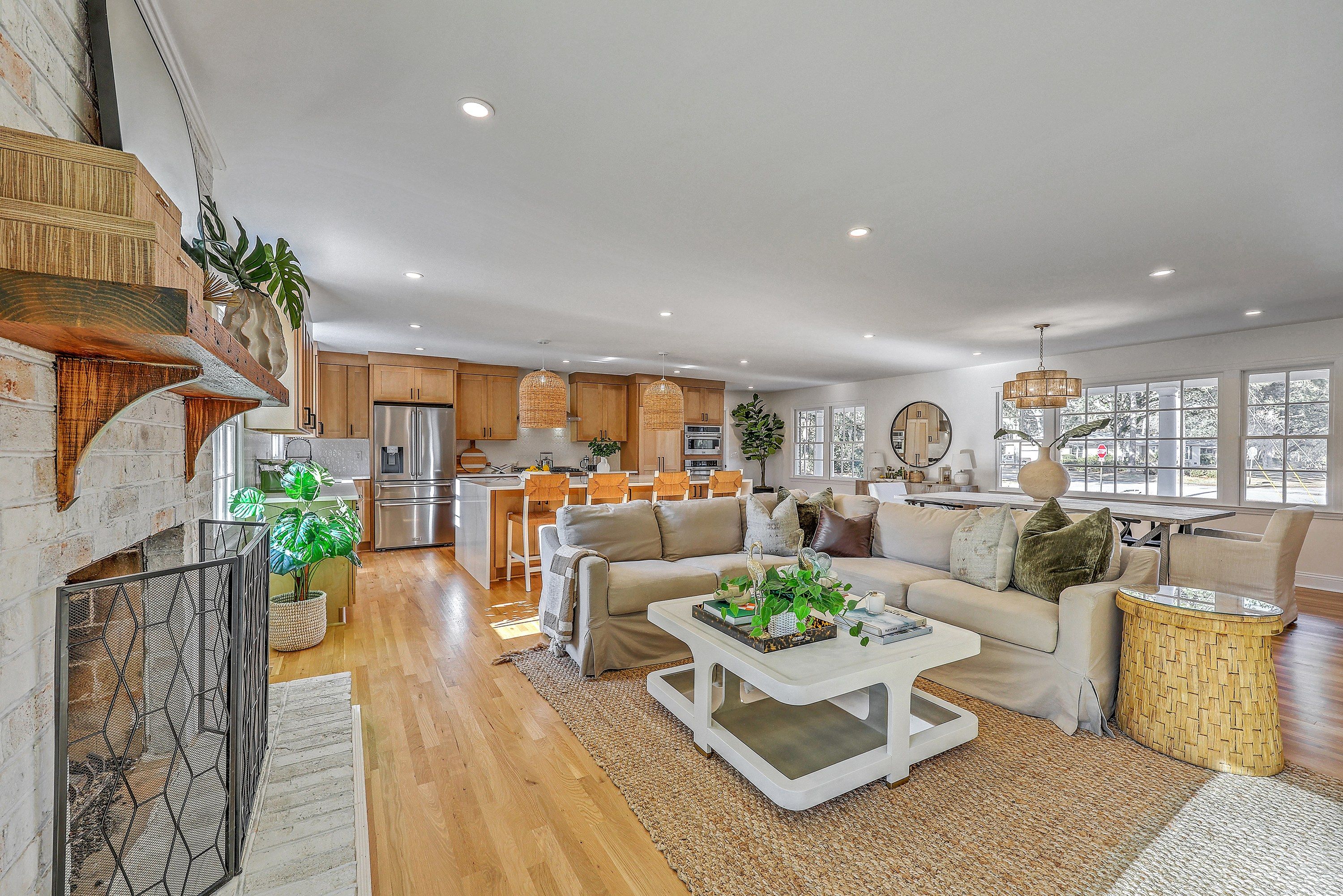 Open living room with brick fireplace flowing to the kitchen and dining area